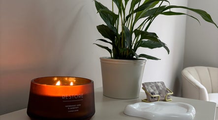 Tranquil setting at Alora SkinSpecialist, Birmingham, England, GB with a candle and lush plant.