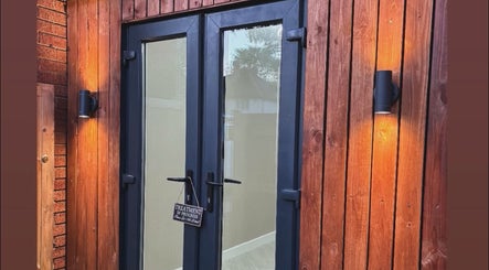 Elegant wooden entrance at Alora SkinSpecialist in Birmingham, England, GB, warmly lit for a tranquil welcome.