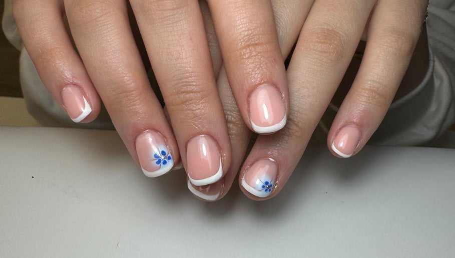 Elegant French manicure with blue floral design at Molly’s Nail Club, Birmingham, England, GB.