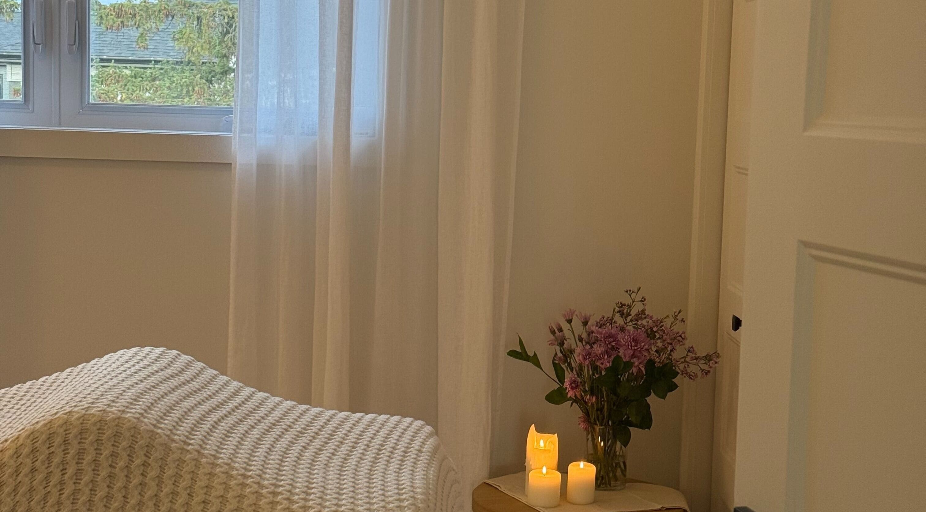 Peaceful treatment room at Melina Esthetique, Terrebonne, Québec, CA with soft lighting, candles, and flowers.