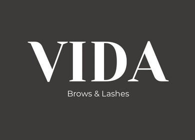 Stylish white logo of Vida Brows & Lashes, Hamilton, Scotland, GB on a dark background.