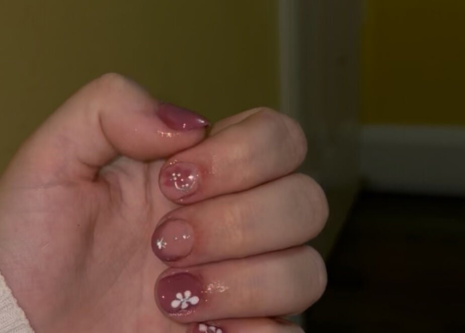 Close-up of floral nail art at CM Biab, Filton, England, GB showcasing intricate white flower designs.