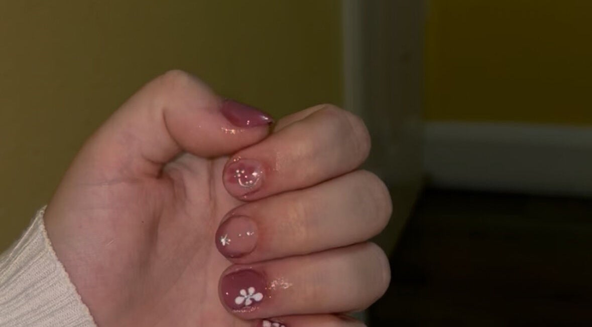 Close-up of floral nail art at CM Biab, Filton, England, GB showcasing intricate white flower designs.