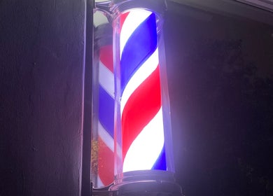 Illuminated barber pole at night outside EXODUS BLENDS, Umhlanga, Kwazulu-natal, ZA.
