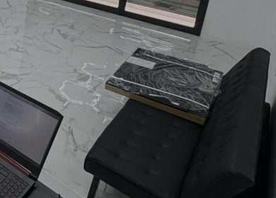 Interno Dagostreet Barber, Mombretto, Lombardia, IT, con pavimenti in marmo e divano nero elegante.