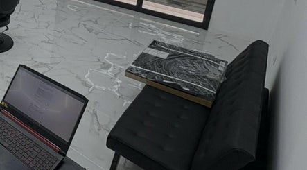 Interno Dagostreet Barber, Mombretto, Lombardia, IT, con pavimenti in marmo e divano nero elegante.