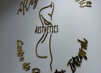 Logo dorado de Estética Rayen Anais Aesthetics en pared blanca en Santiago, Región Metropolitana, CL.
