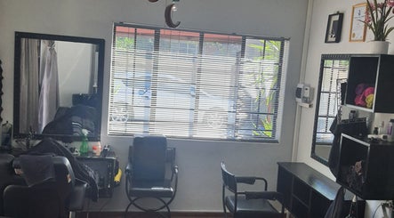 Chic salon interior of Glam Ink Hair in Benoni, Gauteng, ZA with stylish black chairs and sleek mirrors.