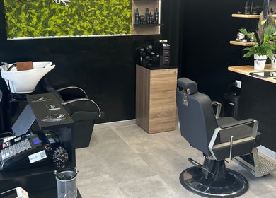 Interno moderno di Double G Barbershop a Selargius, Sardegna, IT con poltrone e piante decorative.