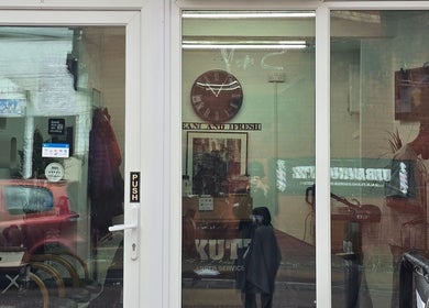 Urban Kutz entrance in Stretford, England, GB, featuring a glass door with visible barbershop interior.