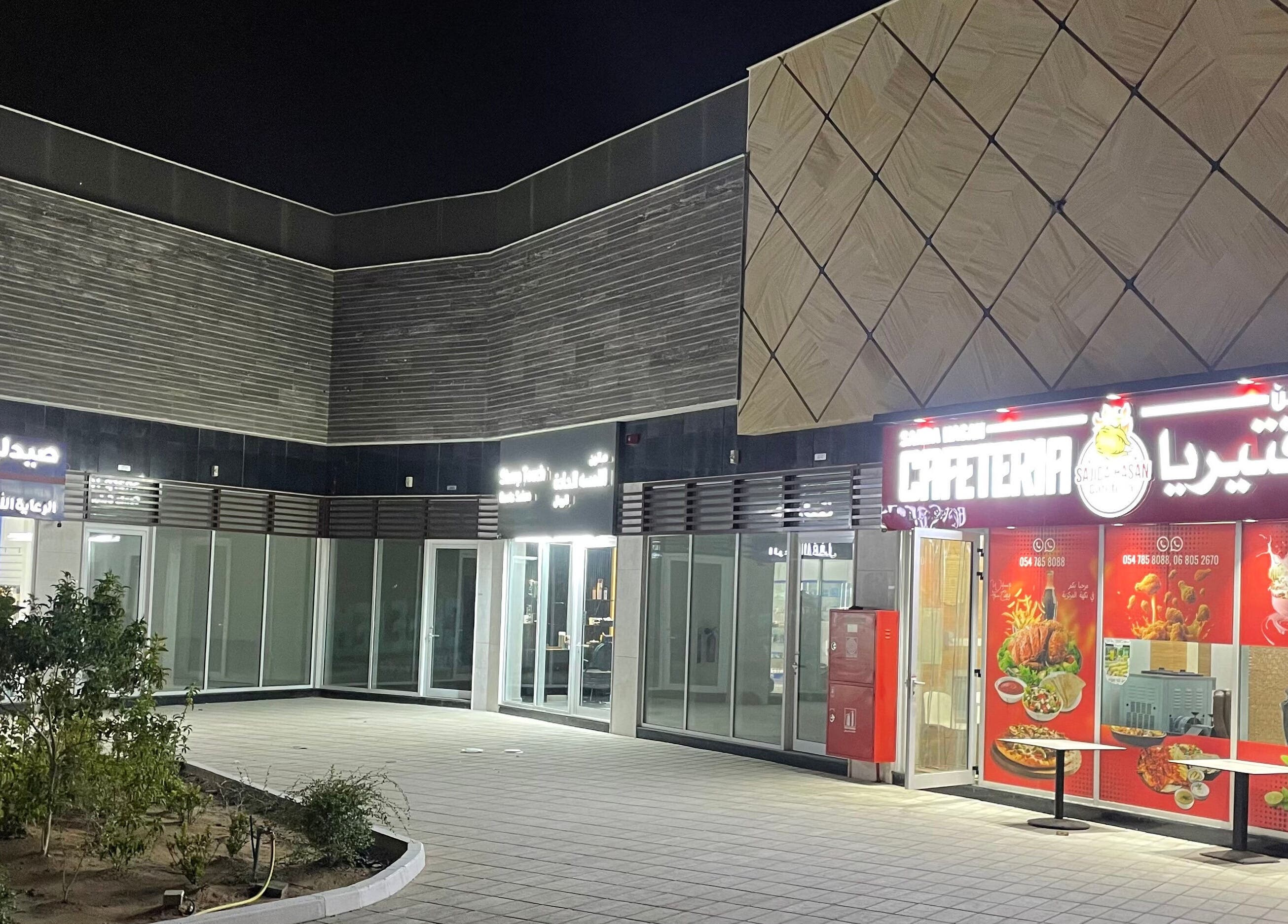 Exterior night view near Sharp Touch Gents Salon, Sharjah, إمارة الشارقةّ, AE, highlighting vibrant lights.