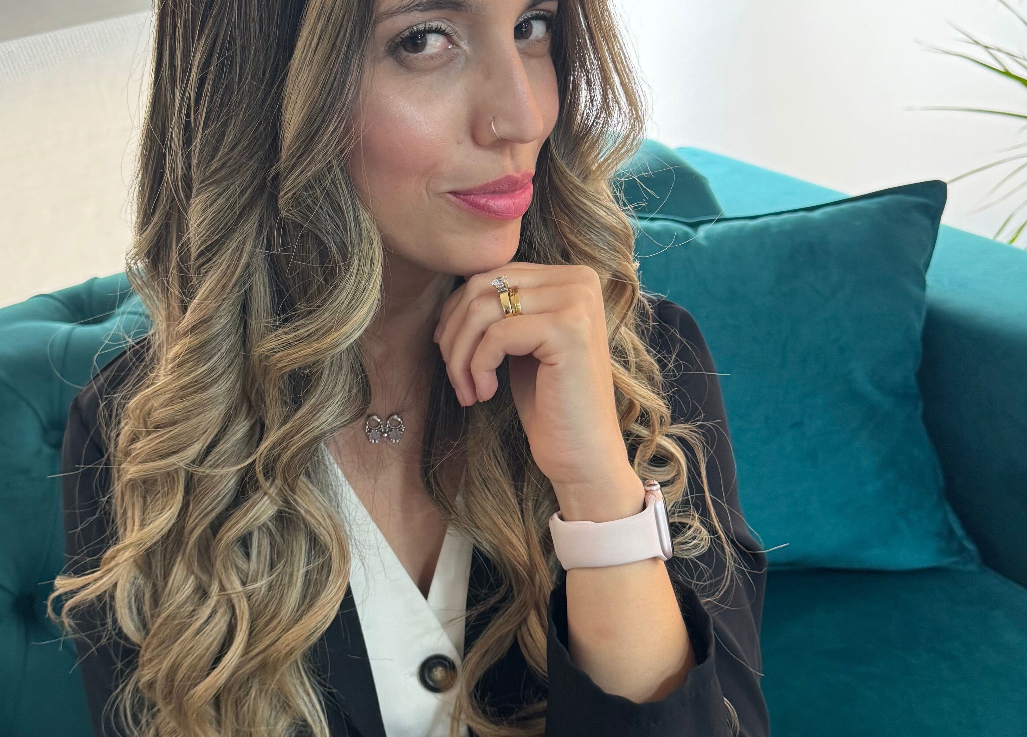 Cliente sorridente no Miminhos Glamour, Freamunde, Porto, PT, com cabelo ondulado, sentada num sofá verde.