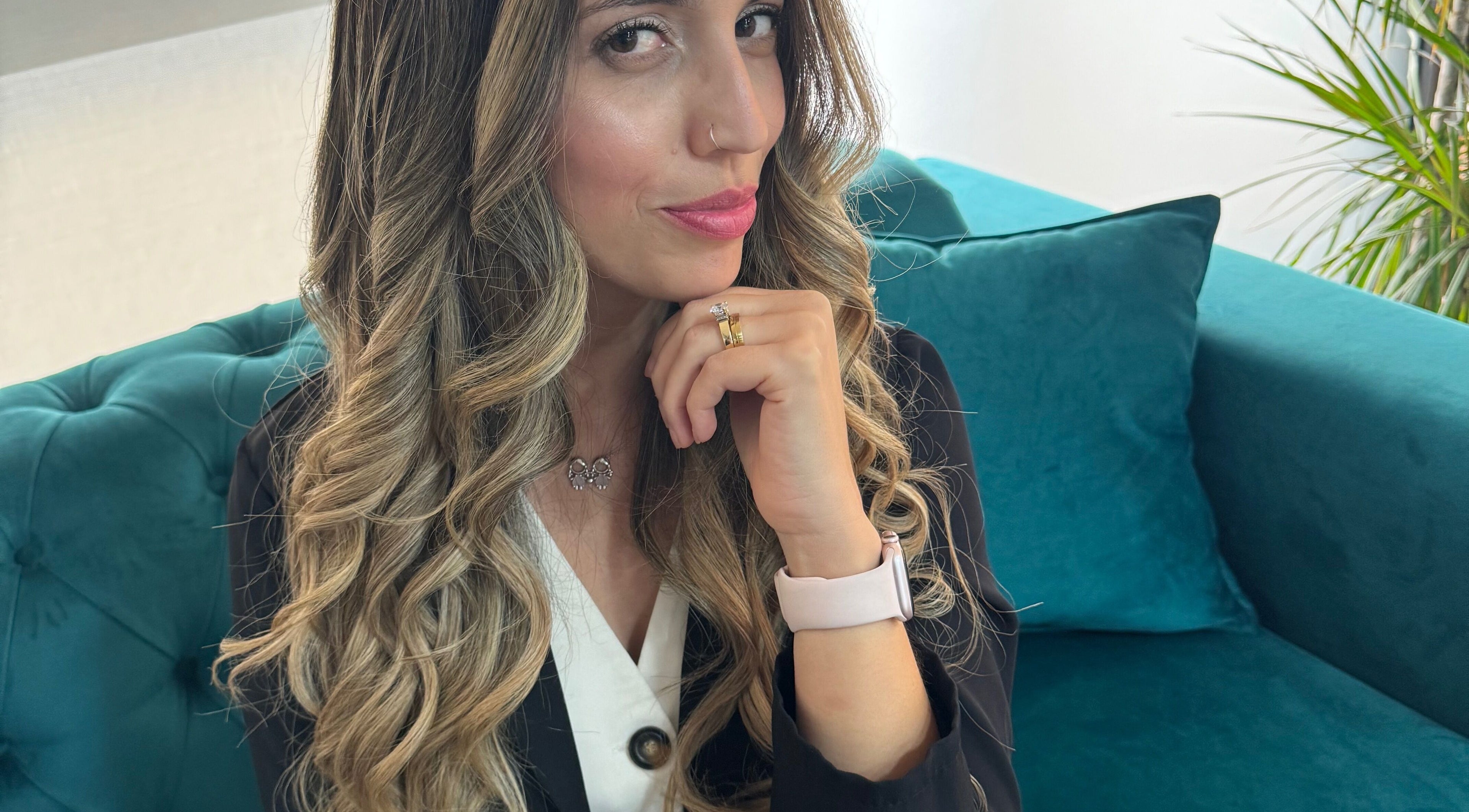 Cliente sorridente no Miminhos Glamour, Freamunde, Porto, PT, com cabelo ondulado, sentada num sofá verde.