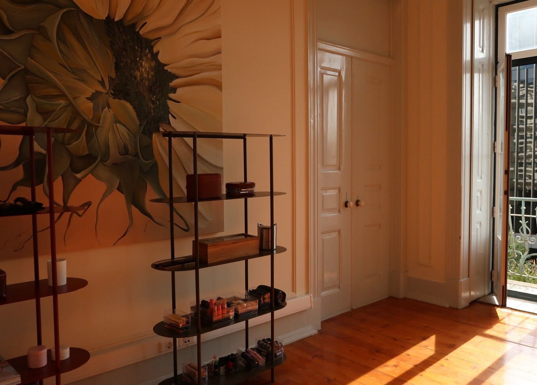 Bright studio at Anna and Make Up, Lisboa, Lisboa, PT, featuring sunflower mural and makeup display.