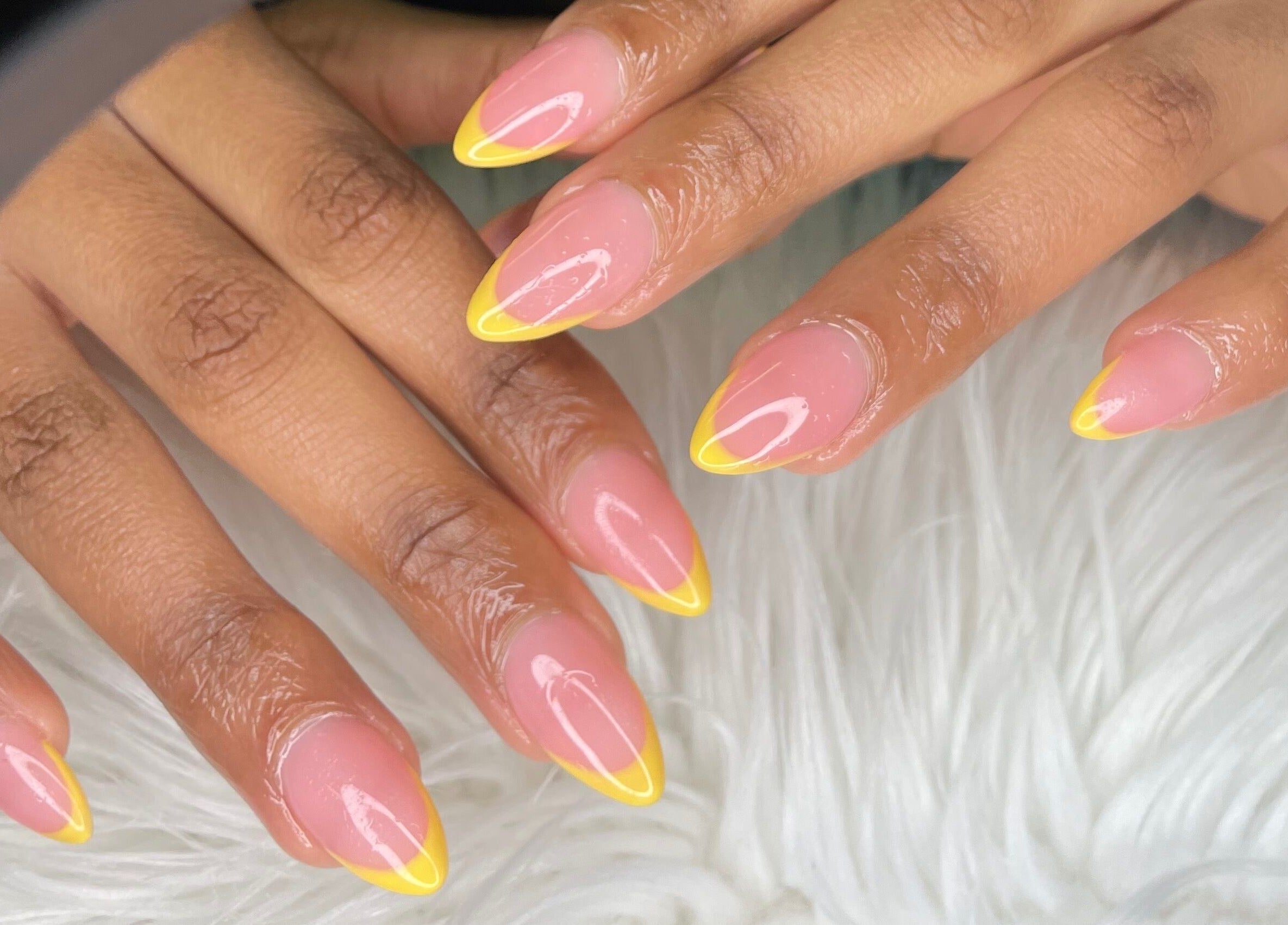 Bright yellow-tipped nails at Wino'S Nail Pub, Gaborone, Gaborone City, BW on a soft white surface.