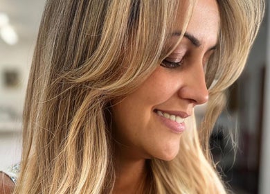 Mulher sorrindo no salão Huana Bueno | Solo Concept em Lisboa, Lisboa, PT com cabelo loiro estilizado.