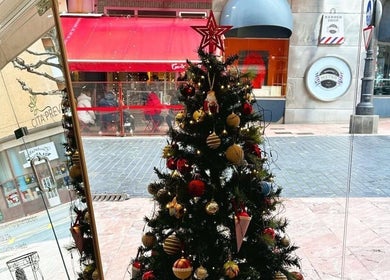 Árbol de Navidad en Jasmin Beauty Studio, Oviedo, ES, visto desde el interior, decorado con adornos brillantes.
