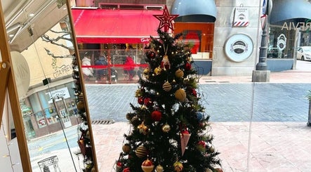 Árbol de Navidad en Jasmin Beauty Studio, Oviedo, ES, visto desde el interior, decorado con adornos brillantes.