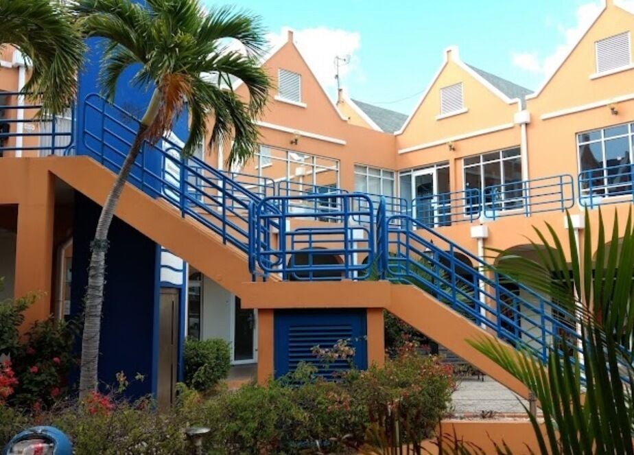 Entrance to Finetouch.ink in Willemstad, Curaçao, CW, featuring vibrant architecture and lush greenery.