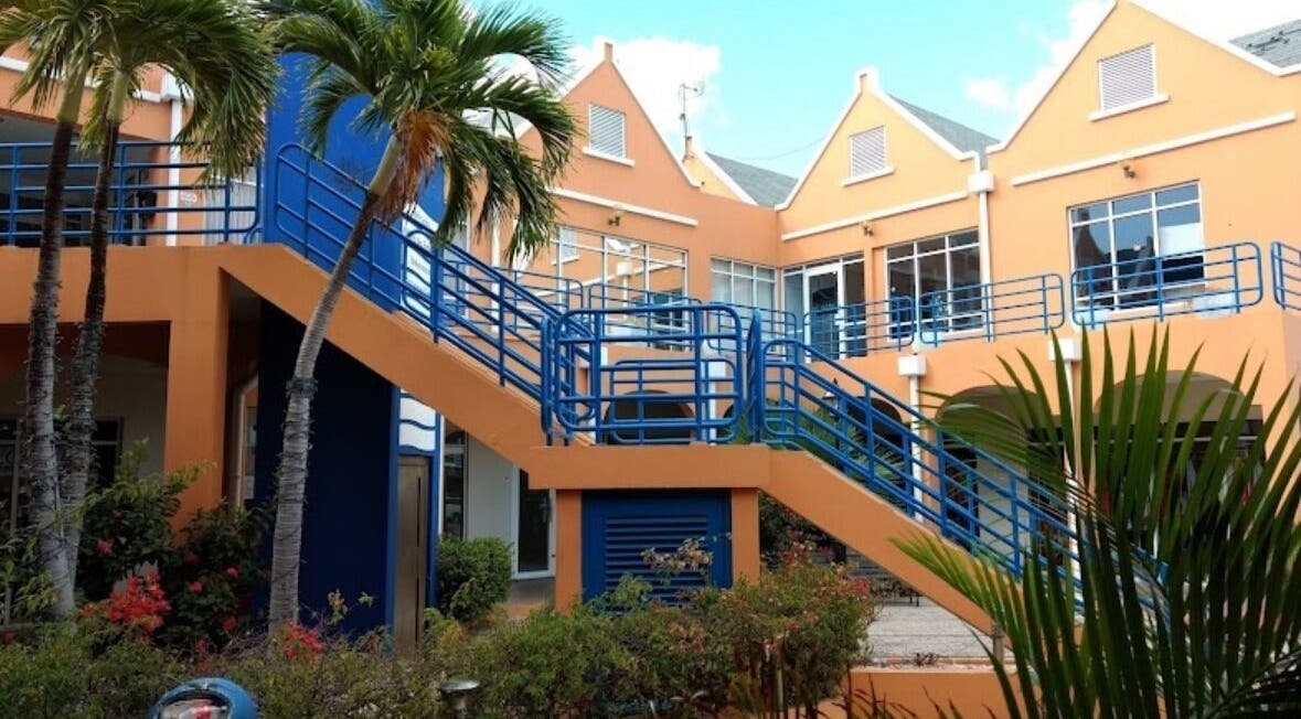 Entrance to Finetouch.ink in Willemstad, Curaçao, CW, featuring vibrant architecture and lush greenery.