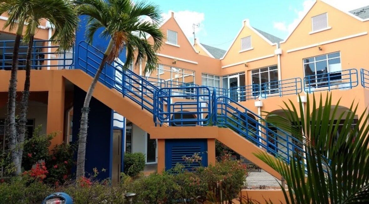 Entrance to Finetouch.ink in Willemstad, Curaçao, CW, featuring vibrant architecture and lush greenery.