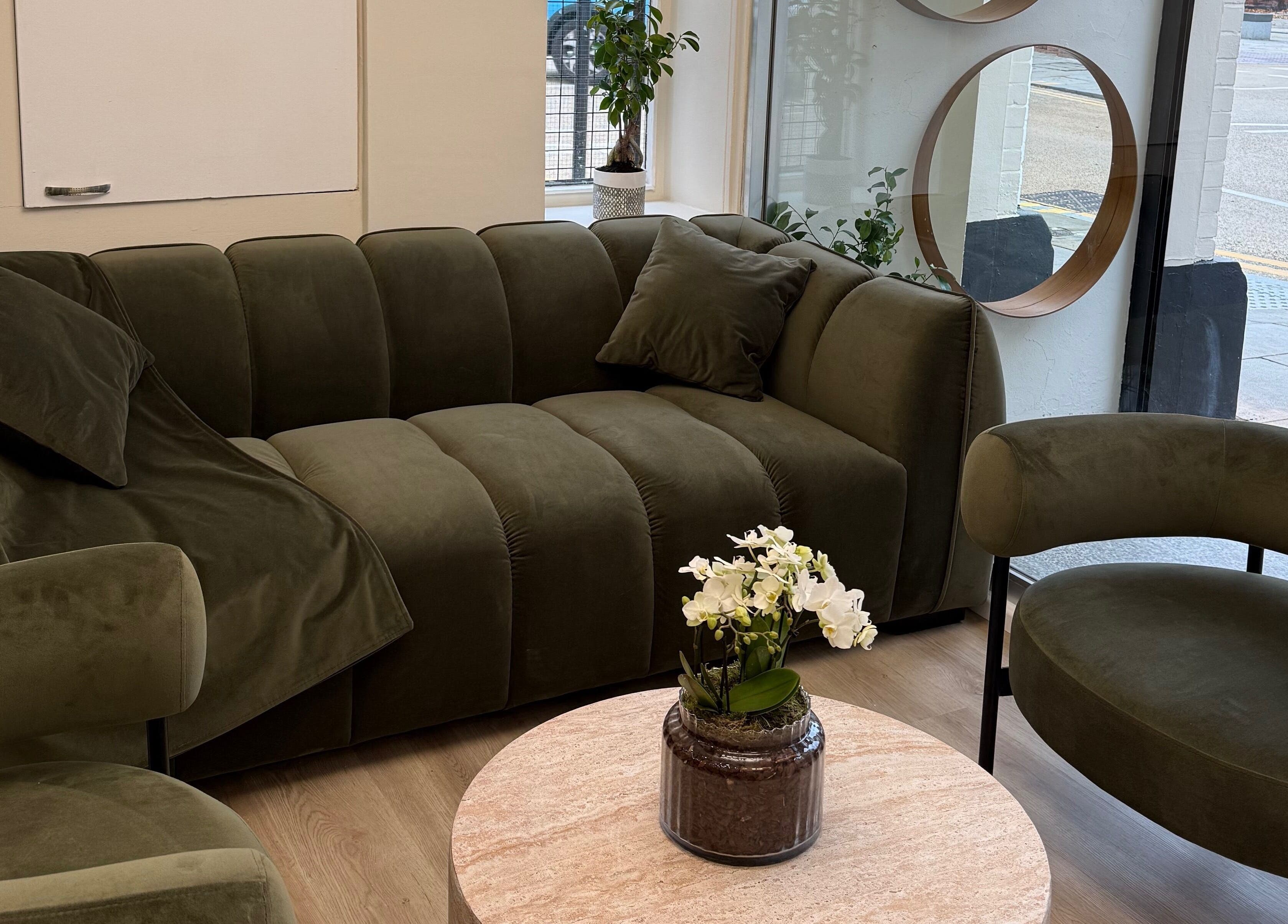 Elegant green lounge at Rejuvenate@45, Stockport, England, GB, featuring a plush sofa and coffee table.