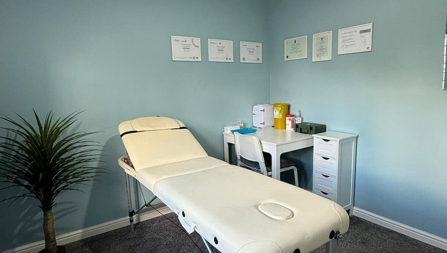 Peaceful treatment room at Key Aesthetics, Swindon, England, GB, with a white therapy bed and certificates.
