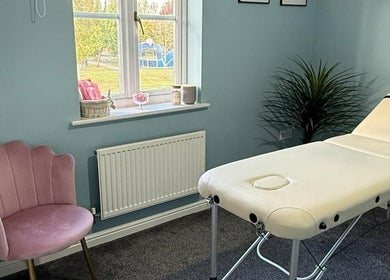 Relaxing treatment room at Key Aesthetics, Swindon, England, GB with a massage table and pink chair.