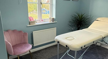 Relaxing treatment room at Key Aesthetics, Swindon, England, GB with a massage table and pink chair.