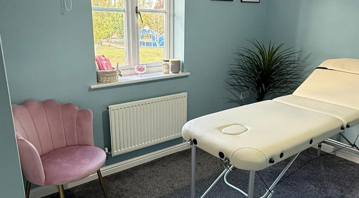 Relaxing treatment room at Key Aesthetics, Swindon, England, GB with a massage table and pink chair.