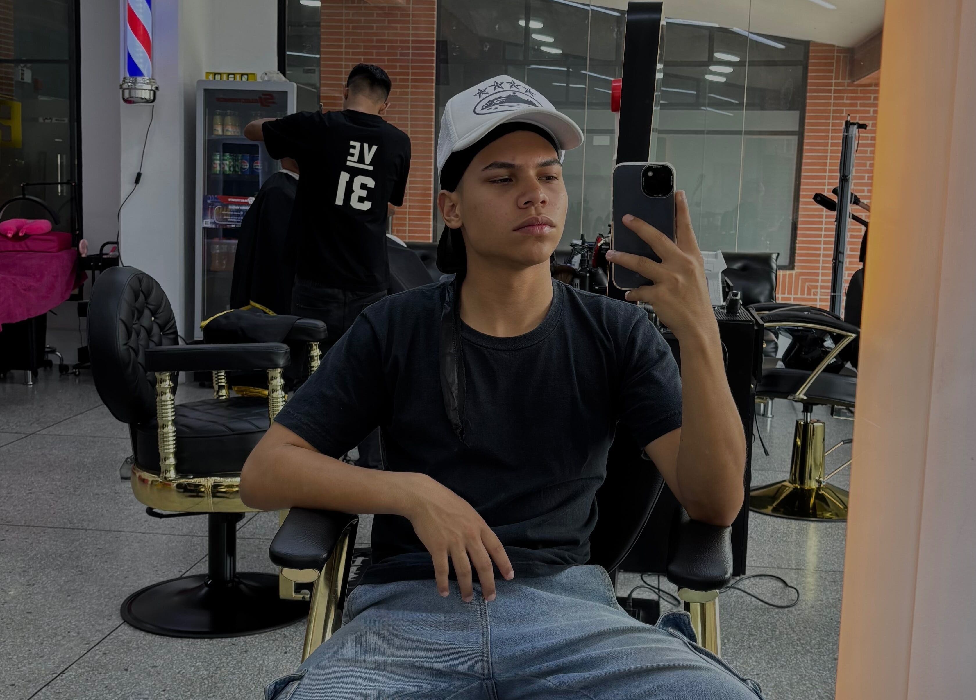 Cliente en Jonvthanbarber, Municipio Carrizal, Miranda, VE, sentado en silla de barbería tomando selfie.