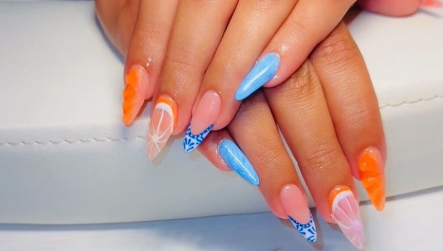 Bright and artistic nail art at Clawed & Cute, Michigan, Michigan, US; featuring orange and blue designs.