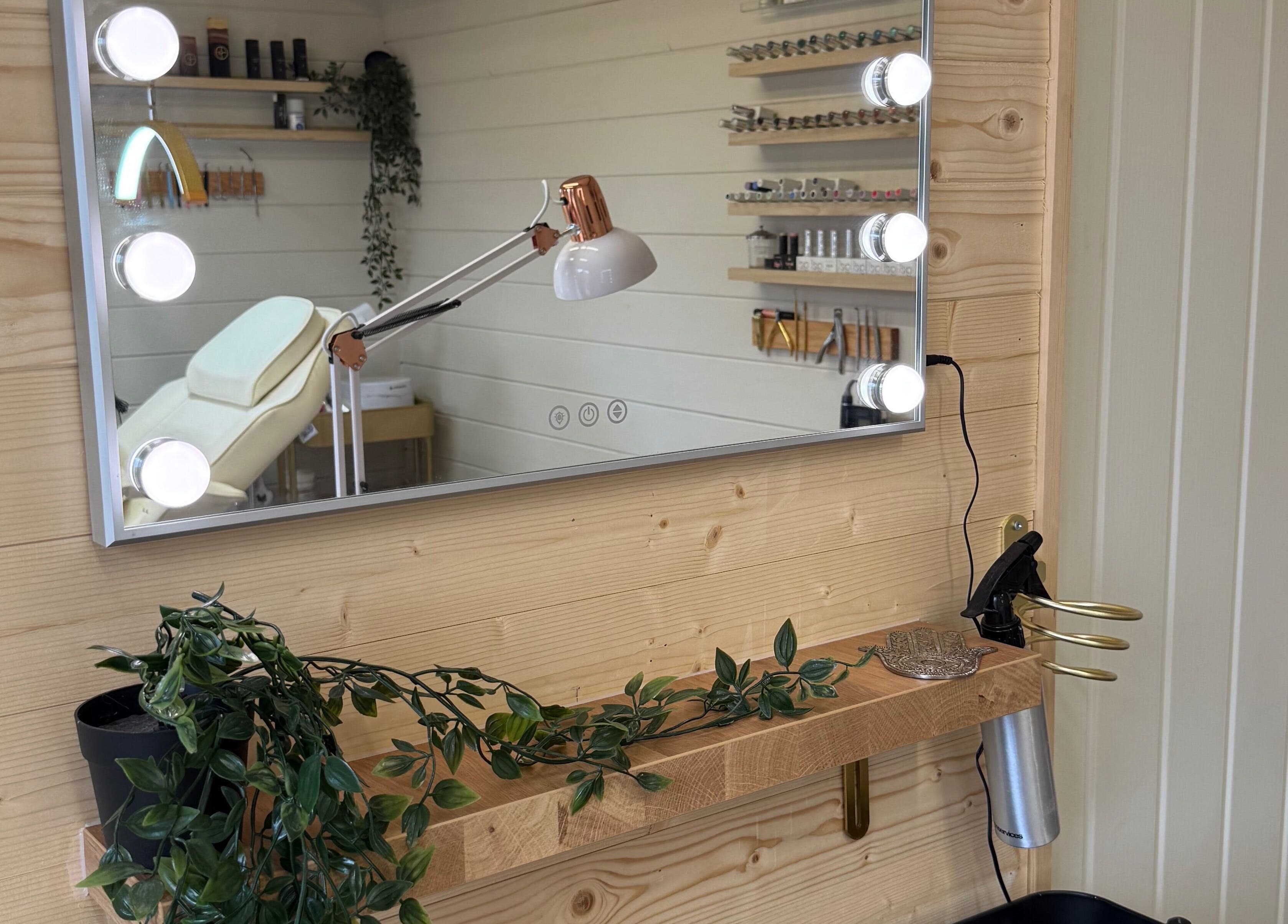 Stylish beauty room at Bonita By Kate in Hyde, England with a lit mirror, greenery, and organized shelves.