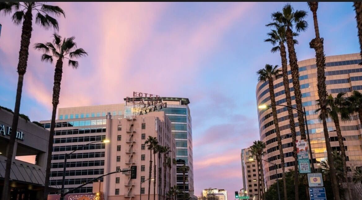 Cityscape near Prestige Eyebrows in San Jose, California, US with palm trees against a pink sky.