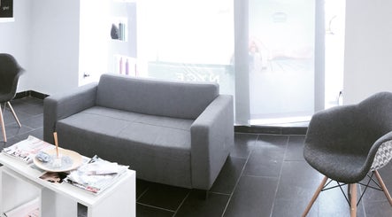 Acogedora sala de espera en Essencial, Barbate, Andalucía, ES, con sofás grises elegantes.