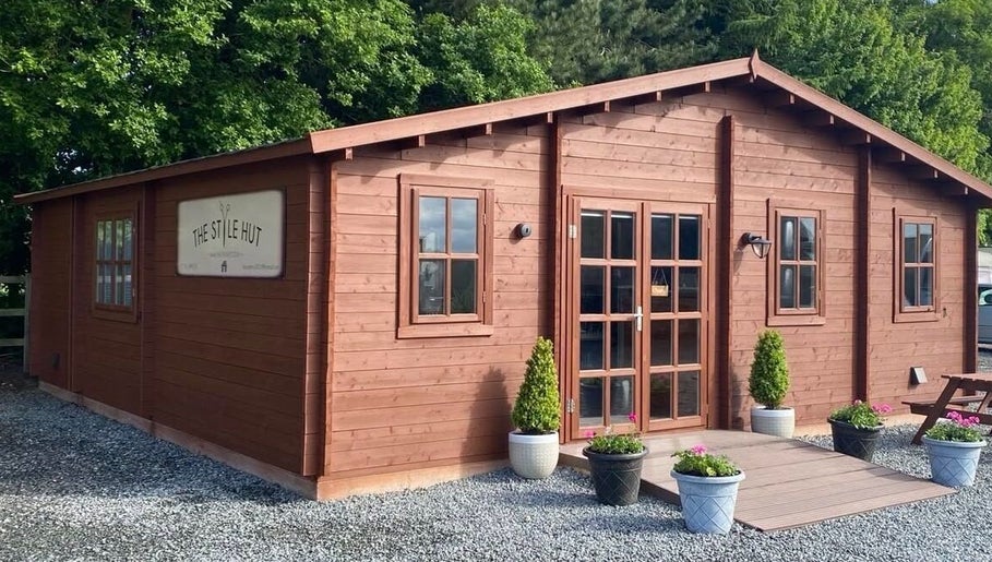Rustic wooden salon exterior of FredtheBarber located in Hull, England, GB, surrounded by greenery.