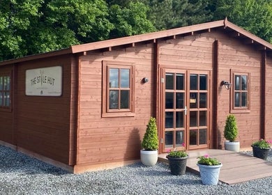 Rustic wooden salon exterior of FredtheBarber located in Hull, England, GB, surrounded by greenery.