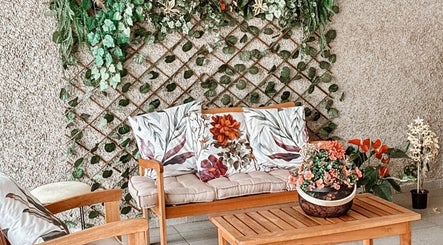 Área de descanso em Lu Delivery Spa, São Paulo, São Paulo, BR, com plantas e almofadas florais.