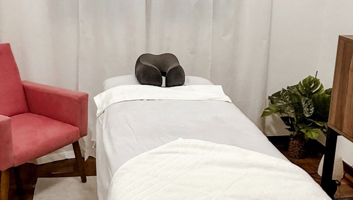 Sala de massagem no Lu Delivery Spa, São Paulo, São Paulo, BR, com cadeira rosa e decoração relaxante.