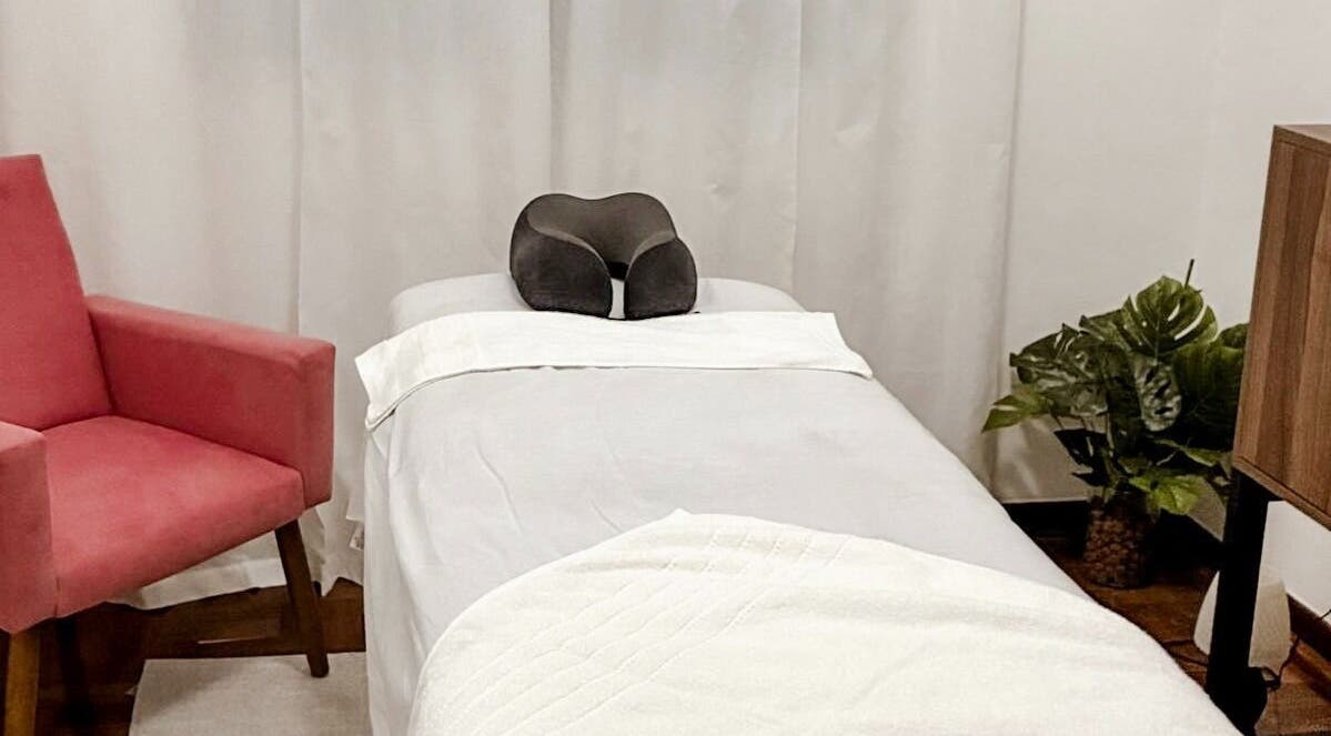 Sala de massagem no Lu Delivery Spa, São Paulo, São Paulo, BR, com cadeira rosa e decoração relaxante.