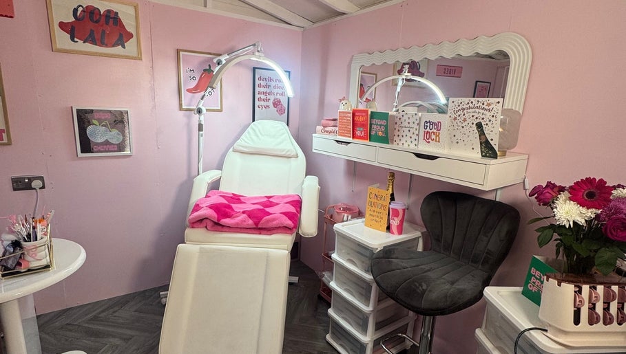 MK Beauty Hut, Coleraine features a stylish pink treatment room adorned with flowers and cozy decor.