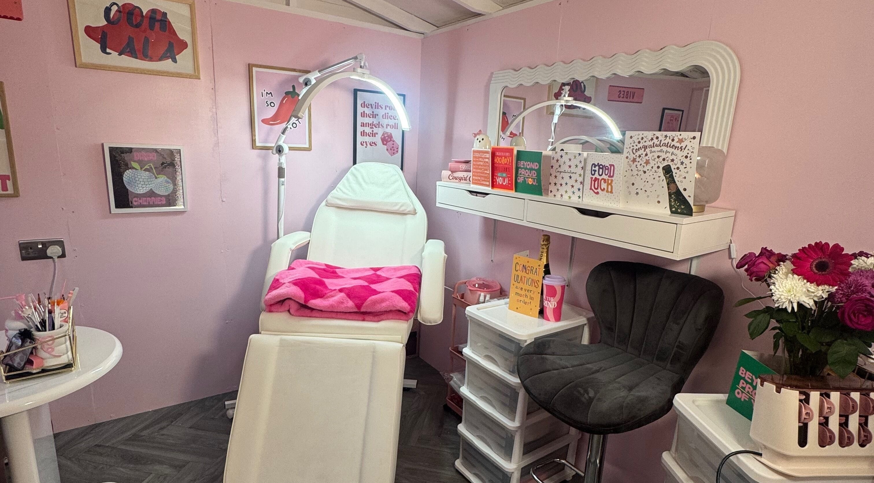 MK Beauty Hut, Coleraine features a stylish pink treatment room adorned with flowers and cozy decor.