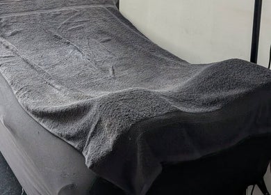 Table de massage avec serviette grise à Amandine Cils, Uchaud, Occitanie, FR, pour soins de bien-être.