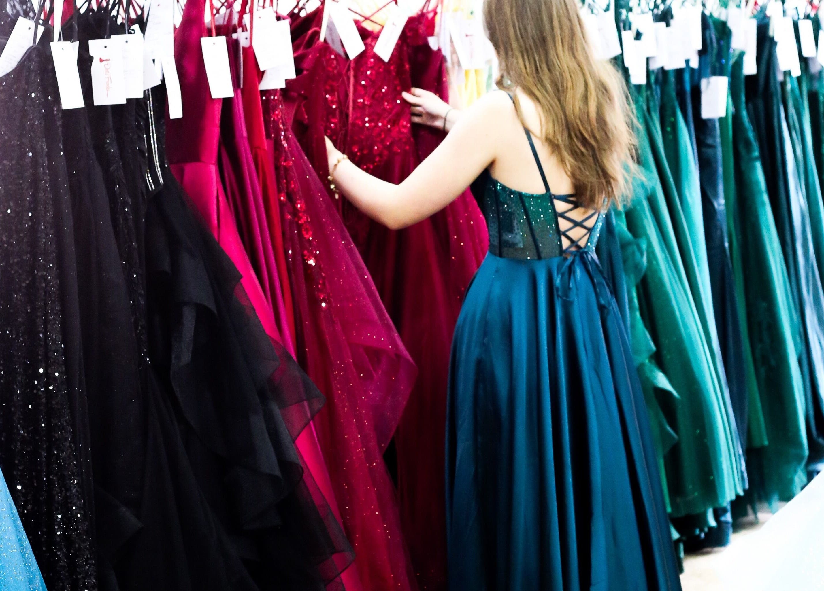 Shoppers browsing elegant gowns at Dot's Frocks, Manchester, England, GB for unique dress options.
