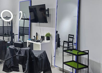 Interior moderno do Opog's Barbershop em Gaia, Porto, PT, destacando cadeira e espelho iluminado.
