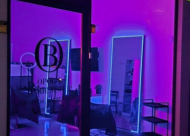 Interior moderno de Opog's Barbershop em Gaia, Porto, PT, com luzes de néon vibrantes.