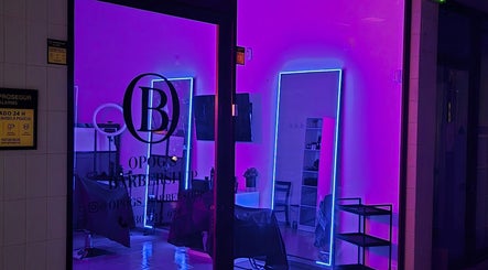 Interior moderno de Opog's Barbershop em Gaia, Porto, PT, com luzes de néon vibrantes.