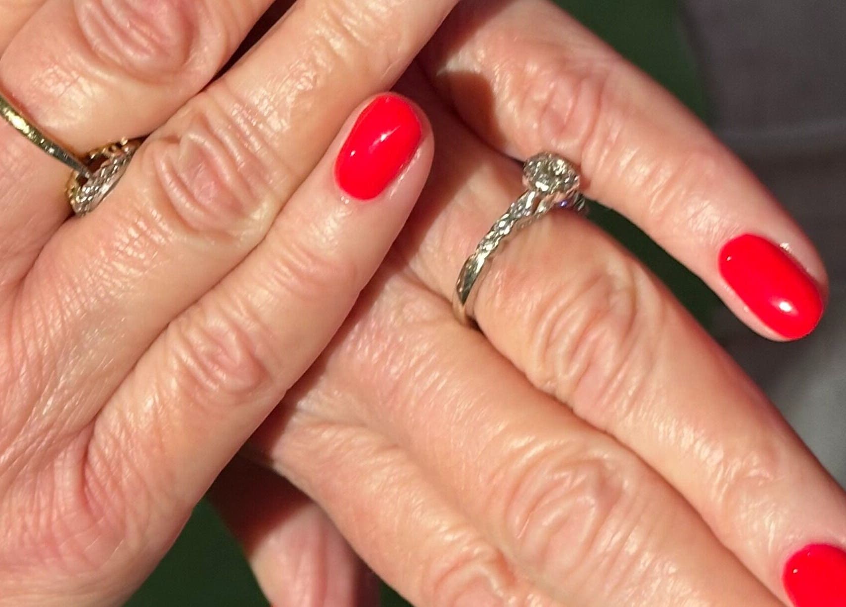 Vibrant red manicure at My Nail Muse, Sheffield, England, GB showcasing elegant rings and polished nails.
