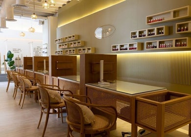 Modern interior of Nails Glow - Al Rawdah, Riyadh, showcasing nail polish wall display and cozy seating.