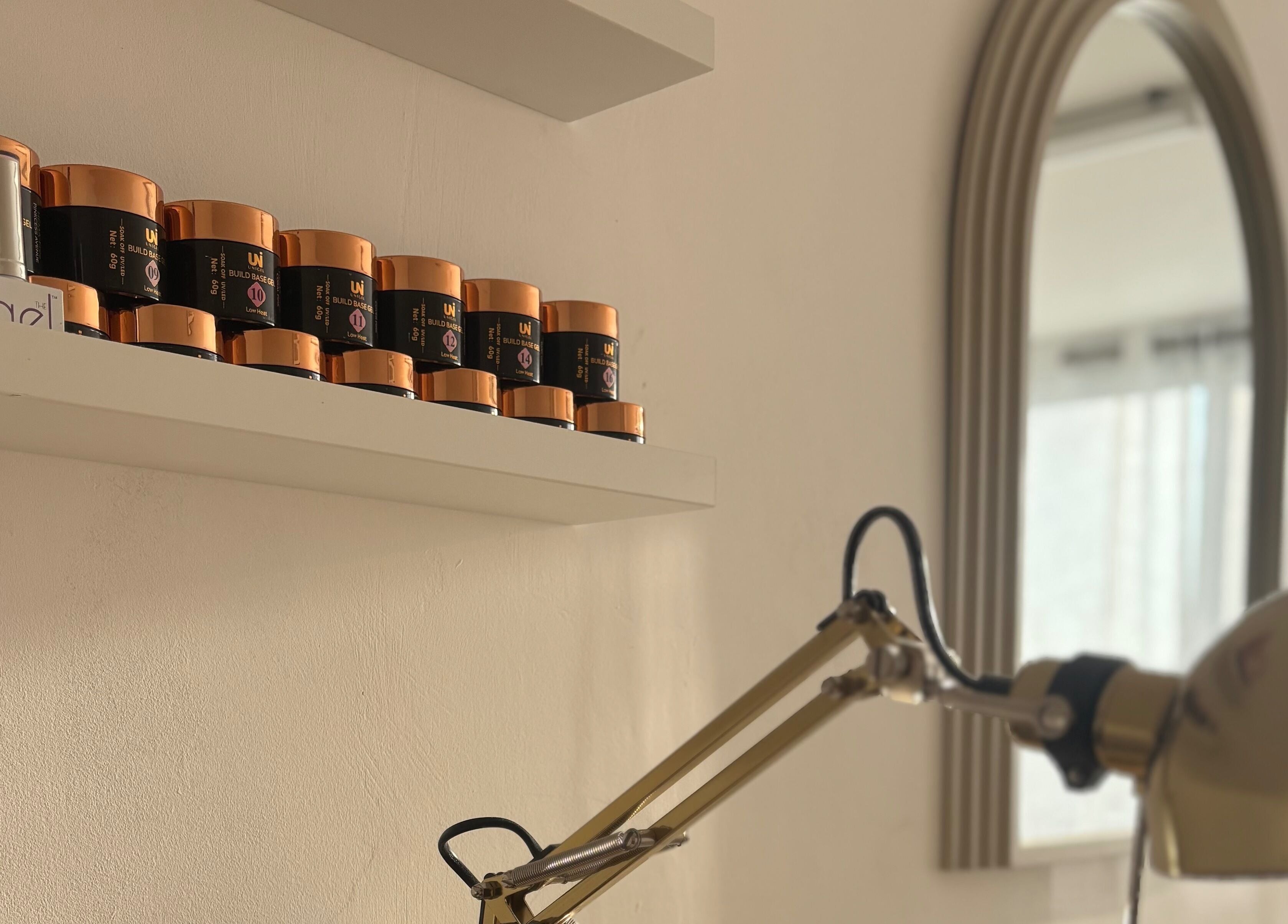 Shelf with nail products at THE NAIL SOCIETY BY ANITA, Rochester, England, GB. Elegant workspace with mirror.